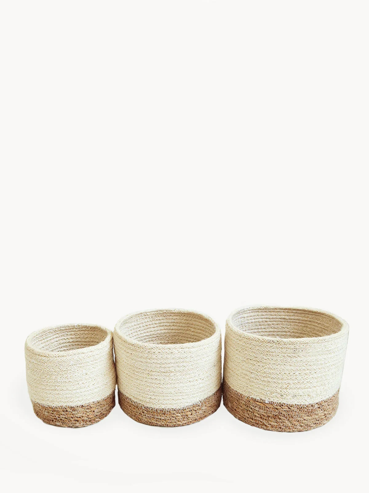 Set of three round woven baskets with natural beige and brown colors on white background