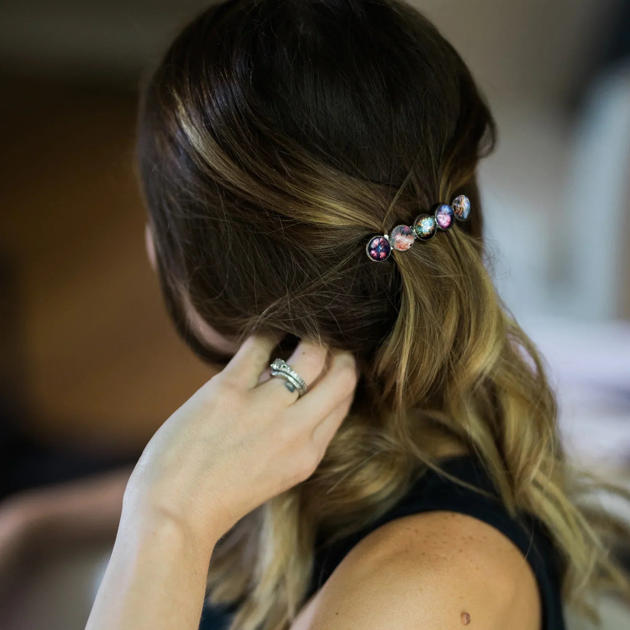 Woman with blonde hair wearing a galaxy-themed hair clip and wedding rings on her hand